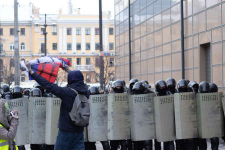 Saint Petersburg, Russia - 31 January 2021: Activist with Russian flag next to riot police with...
