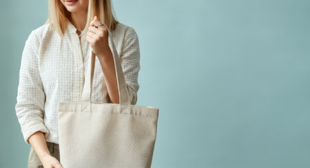 Woman is holding a white bag. The bag is made of cloth. The woman is smilingの素材
