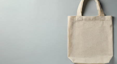 White bag is hanging on a wall. The bag is empty. The wall is grayの素材
