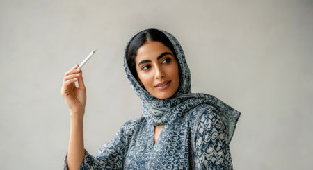 Woman wearing a blue scarf and holding a pen. She is smiling. The pen is whiteの素材