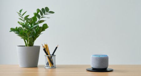 Small potted plant sits on a wooden table next to a pencil holder and a cup. A small speaker is also placed on the table, adding a touch of modernity to the sceneの素材