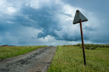 Broken Road Sign By A Country Lane Under A Stormy Sky