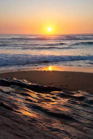 Rocks on the beach in the evening, the sun is hiding in the horizon, north of Spain