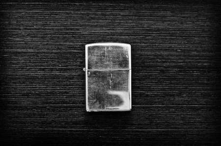 Iron lighter on a dark wooden table in black and whiteの写真素材