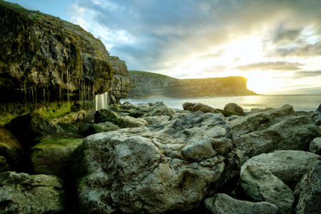 Landscape of a rocky shore with green moss and a nice sunset in Cantabria, Spainの写真素材