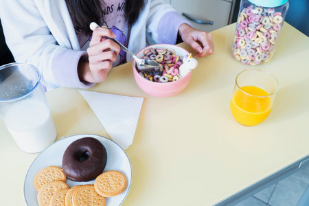 Young woman with unicorn coat preparing some color cereals and an Orange Juice for a funny breakfastの写真素材