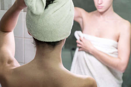 Young woman drying up her hair and body with the towels after a shower and body care in front of the...
