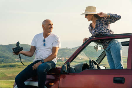 Aged Couple taking a photo and traveling through the coast in their 4x4 convertible car