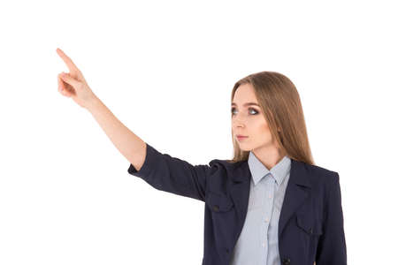 Look over there! Curious young businesswoman in suit pointing away while standing against white backgroundの写真素材