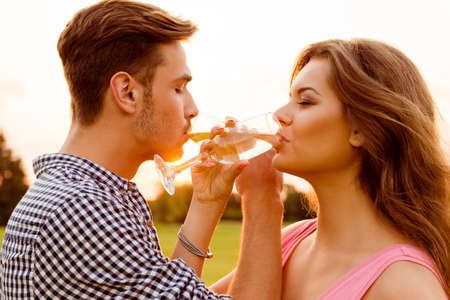 young couple drinking champagne at sunsetの写真素材