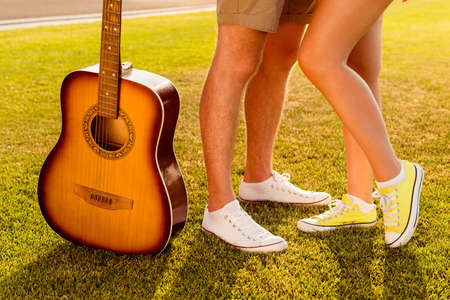 Man's and woman's legs with guitar. Couple in love on the lawnの写真素材