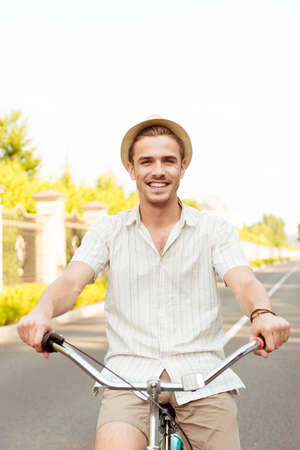 Happy young man in hat riding a bicycleの写真素材