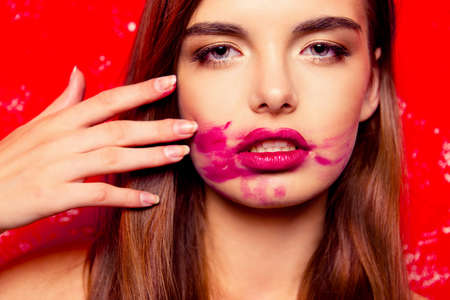 beautiful girl on a red background rubbing lipstickの写真素材