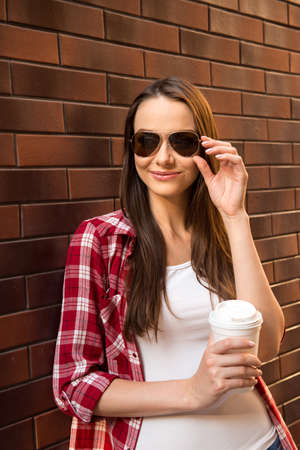 Girl in casual style with cup of coffee and glassesの写真素材