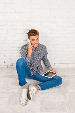 man sitting on the floor with digital tablet and phoneの写真素材