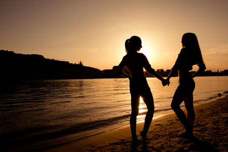 silhouettes of girlfriends at sunsetの写真素材