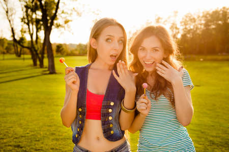 Two astonished amusing sexy girls with lollipopsの写真素材