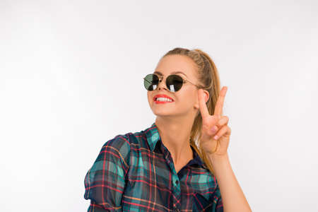 cute girl in a checkered shirt with sunglasses showing two fingersの写真素材