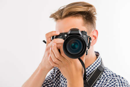 handsome young photographer taking a photo of a viewerの写真素材
