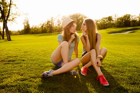 Two sexy girls licking lollipops on the grassの写真素材