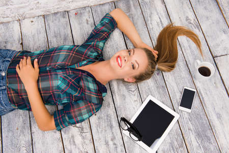Top view of cute girl lying on wood floor and relaxation with tabletの写真素材