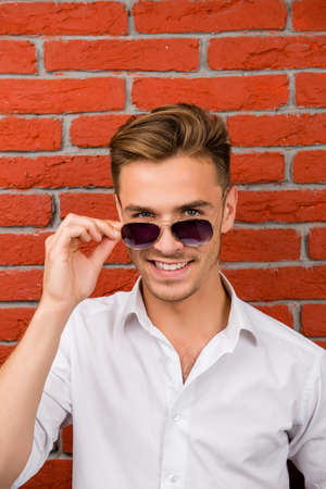 handsome man holdsng his glasses and smilingの写真素材