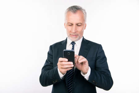 Old handsome businessman writing message on his smartphoneの写真素材