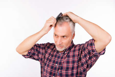 Handsome aged man combing hairの写真素材