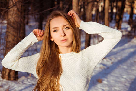 Beautiful girl wearing white sweater in winter forestの写真素材