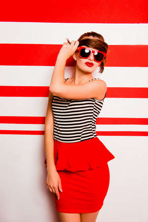 Cute girl with red lips and glasses posing against the striped backgroundの写真素材