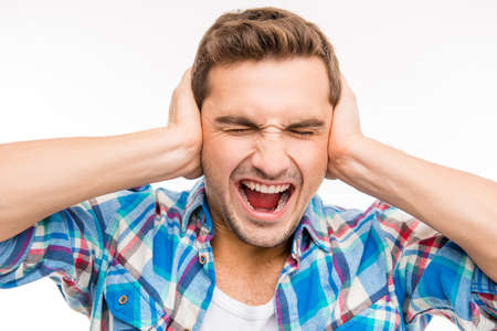 Young man covering his ears and shouting