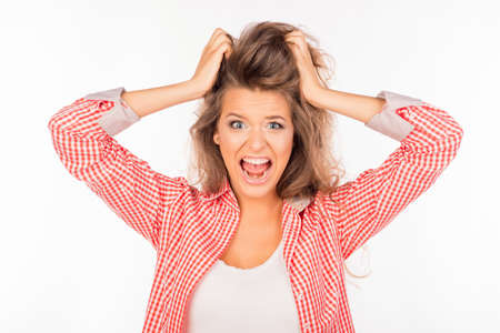 Portrait of crazy young woman shouting and holding hair