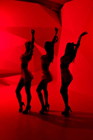 Silhouettes of three sexy posing girlsの写真素材