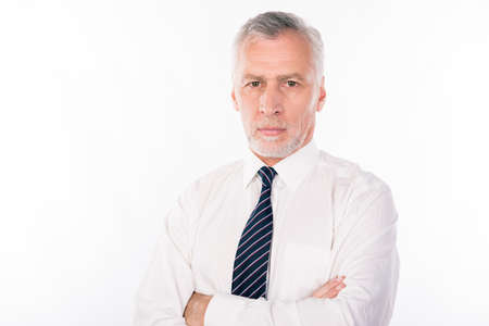 Handsome confident businessman with gray beard crossing handsの写真素材