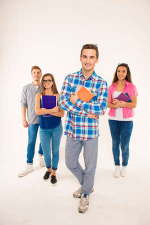 Happy group of students holding books and materials walking straightの写真素材