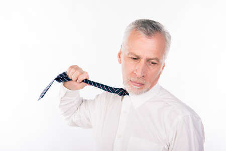 Old businessman choking himself with tieの写真素材