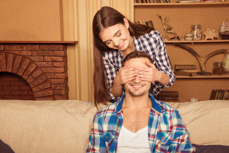 happy girl did surprise her boyfriend, covering his eyes with her handsの写真素材