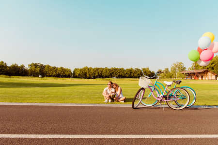 romantic happy couple in love sitting on the grass at their bicyclesの写真素材
