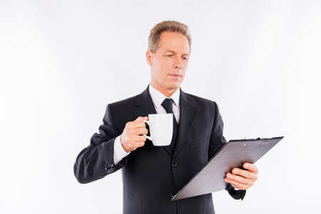 An attractive mature businessman with folder and mug in his handsの写真素材