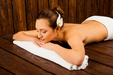 Attractive young girl lying with closed eyes in saunaの写真素材