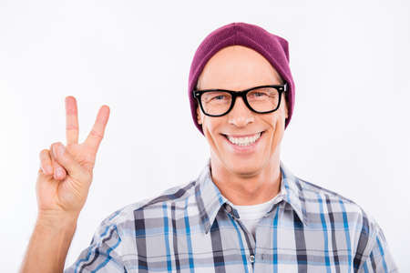 Cute senior man in glasses showing Peace gesture