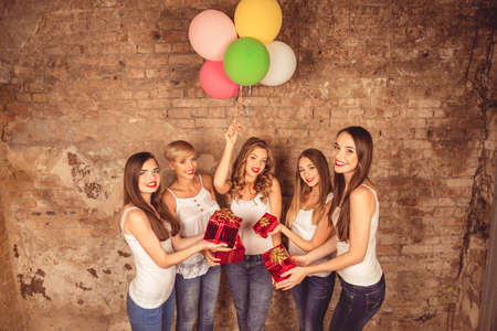 Nice girls celebrating party with red presents and balloonsの写真素材