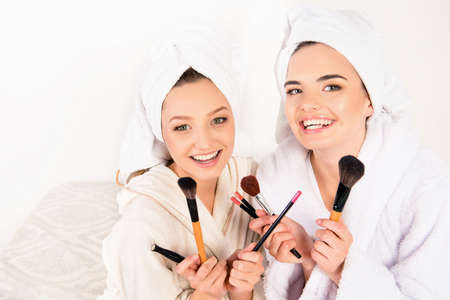 Nice young women holding makeup brushes with towels on their headsの写真素材