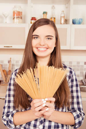Attractive girl holding pasta in the kitchenの写真素材