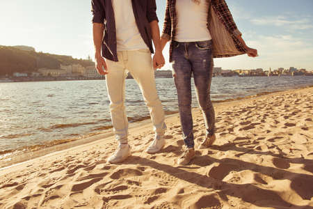 Couple in love holding hands and walking at the beach, image of couple's legsの写真素材