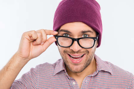 Close up photo of cheerful man in violet cap touching glassesの写真素材
