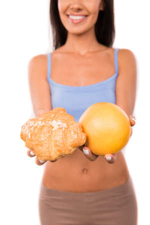 Cute girl chooses between a healthy food and harmful foodの写真素材
