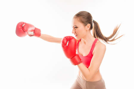 Beautiful strong sportswoman in red boxing gloves striking, side view photo
