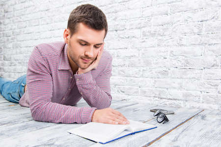 Young man lying on the floor and reading book