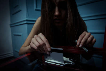 Social problem. Young girl going to inhale cocaine